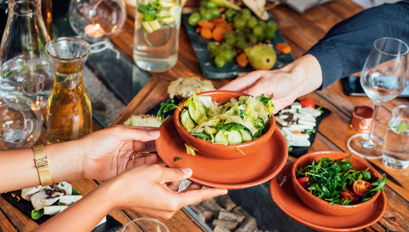 Person passing salad over table