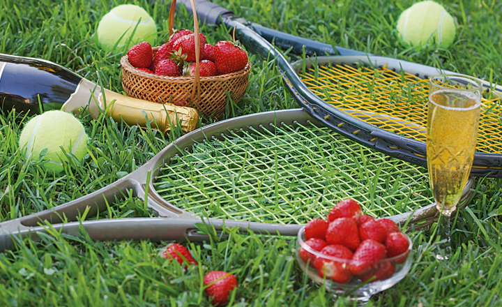 Tennis rackets on grass with punnets of strawberries