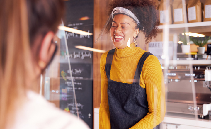 Laughing woman working in cafe with protective visor