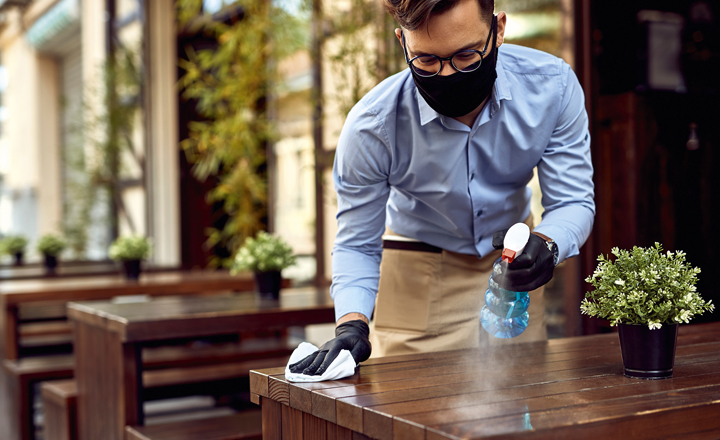 Man in mask cleaning table