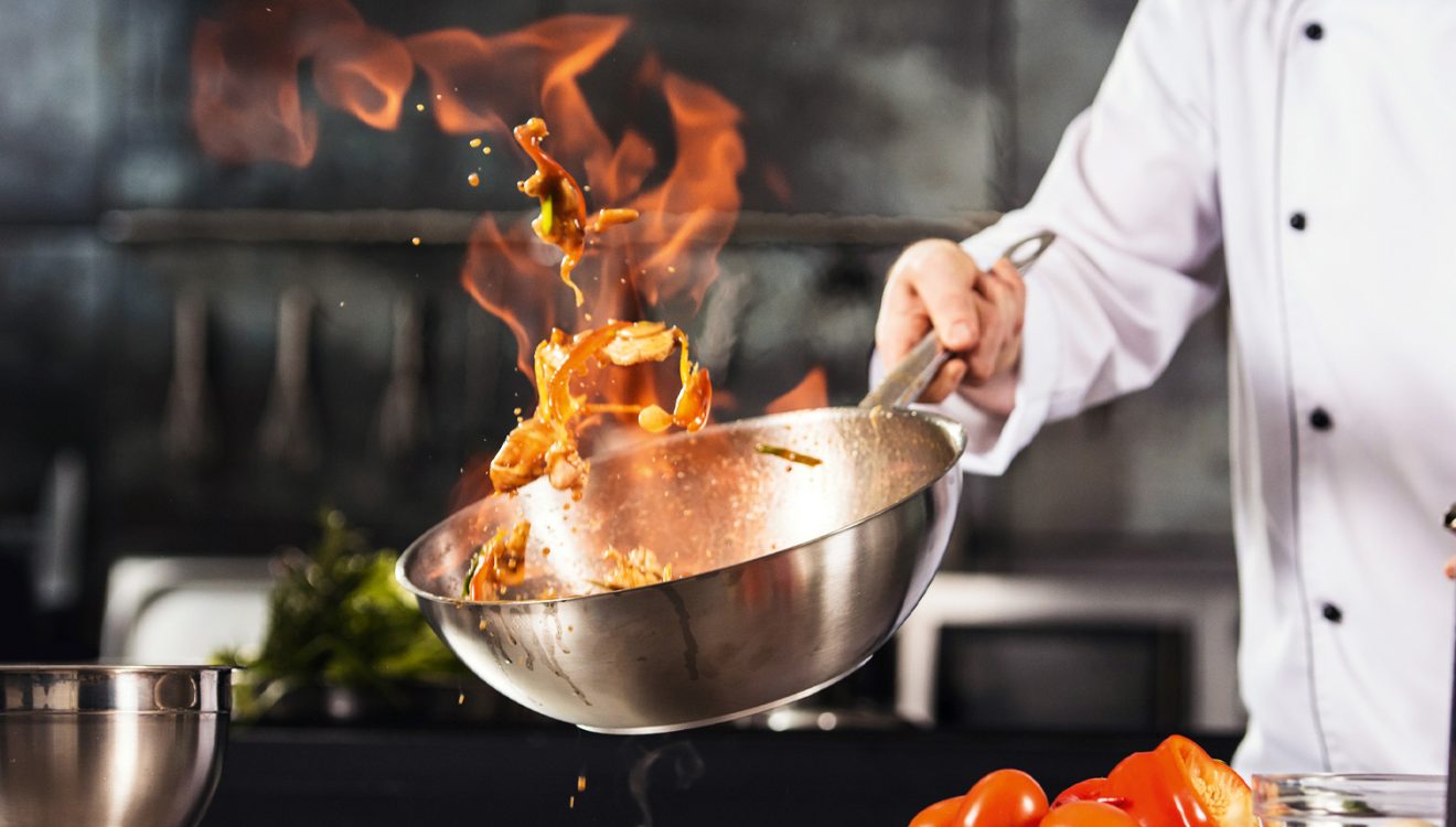 Chef tossing food in flaming wok