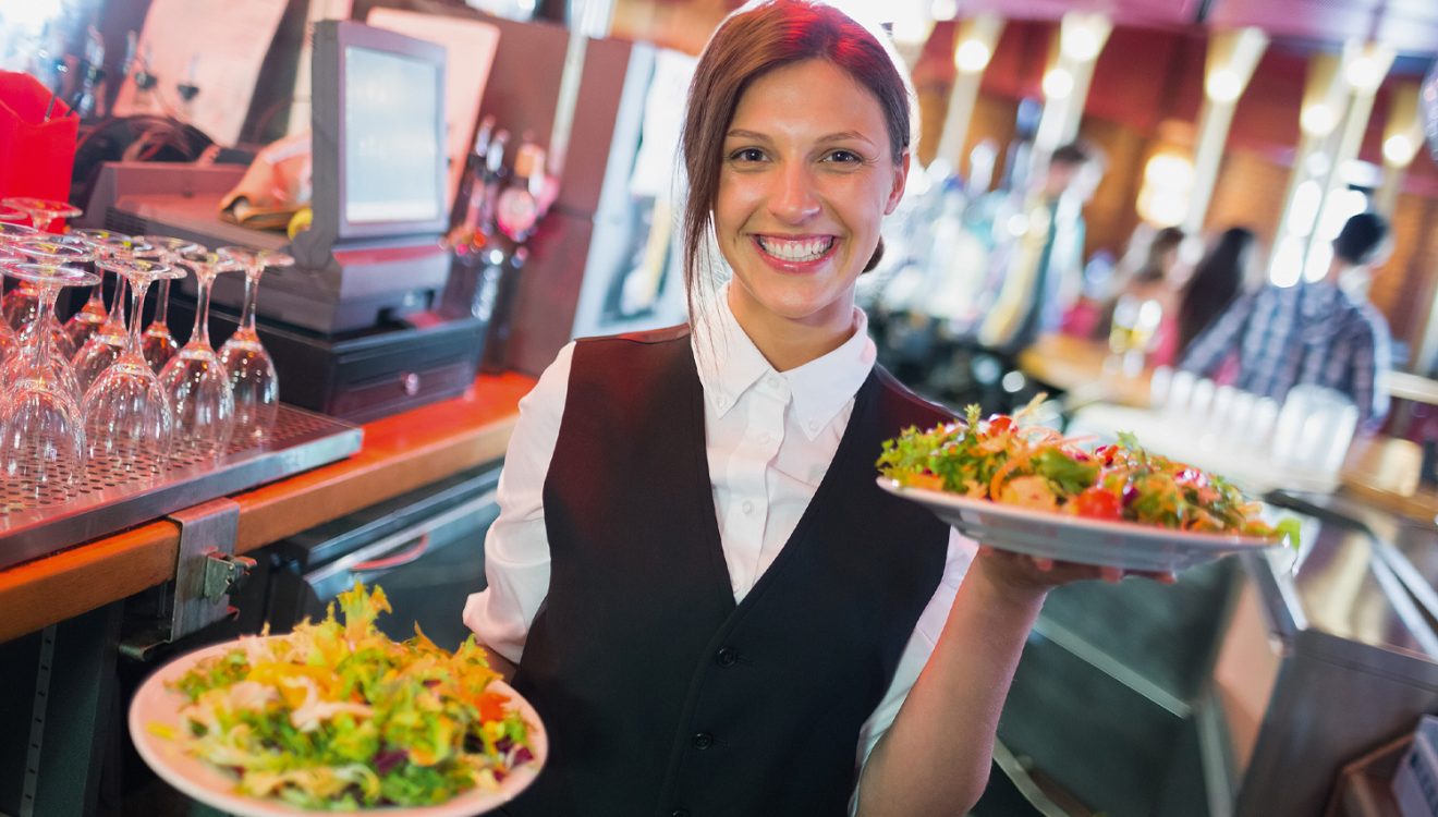 Smiling waitress holding plates of food