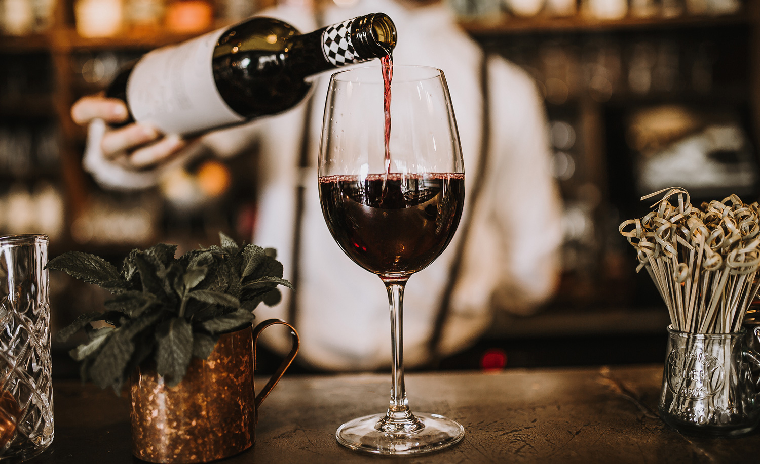 Barman pouring a glass of red wine