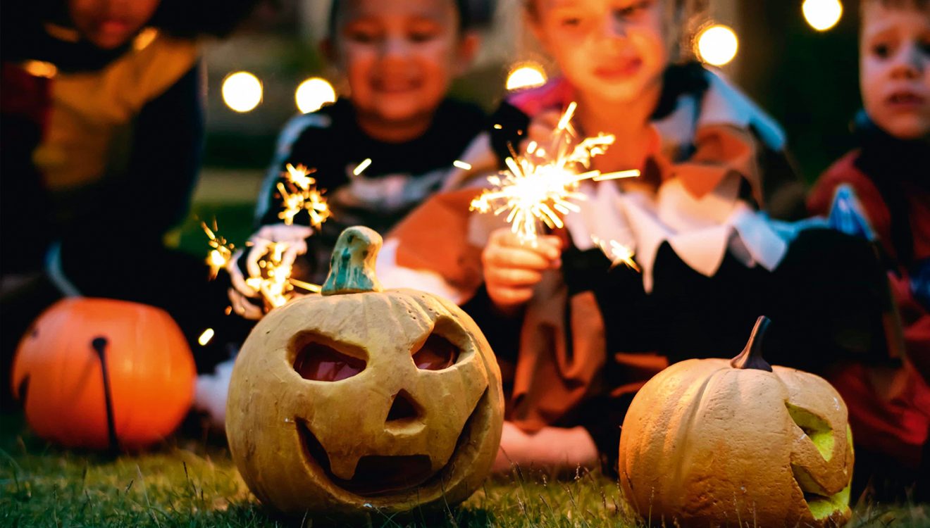 Children with sparklers, pumpkins in foreground