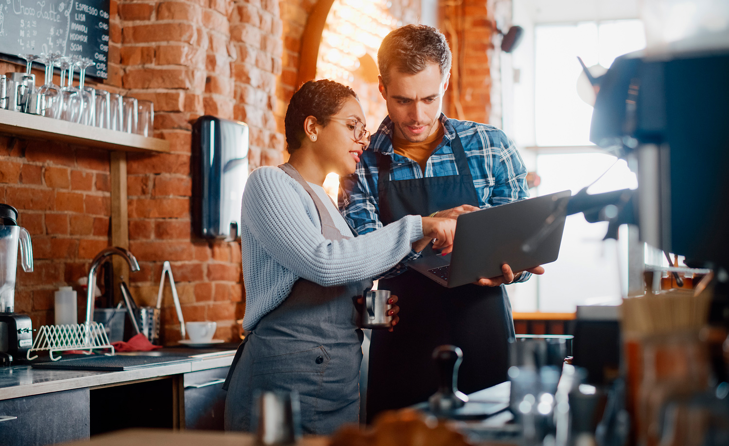 Male and female working in a cafe, looking at a laptop