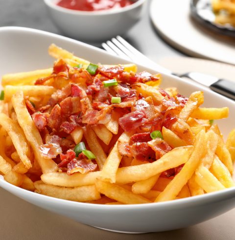 A bowl of loaded french fries with a spicy salsa topping